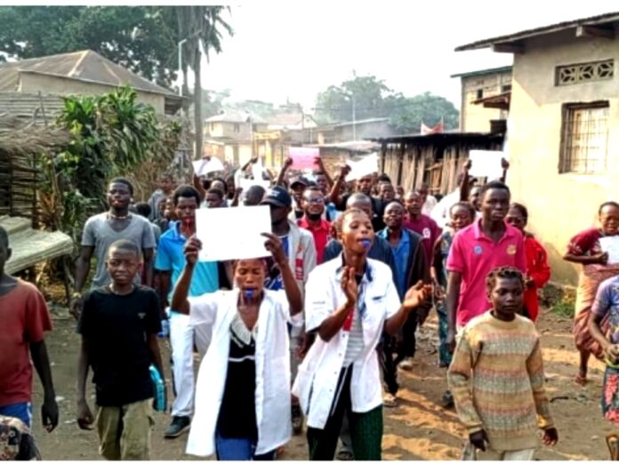 Habitants rassemblés dans une rue de Kasongolunda en signe de protestation, avec des bidons d'eau et des banderoles
