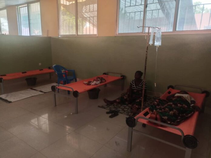 Salle d'hospitalisation avec des lits de fortune et des étagères à médicaments vides dans un centre de santé