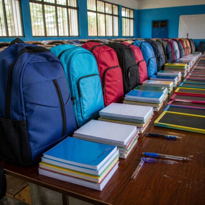 Sacs à dos et cahiers alignés sur une table dans une salle communautaire à Kimbanseke