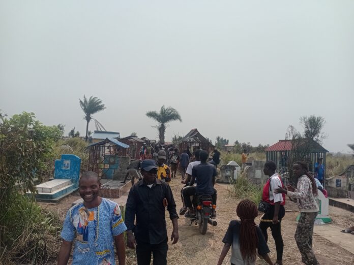 Familles se recueillant et entretenant des tombes dans un cimetière de Kinshasa lors de la Journée du souvenir