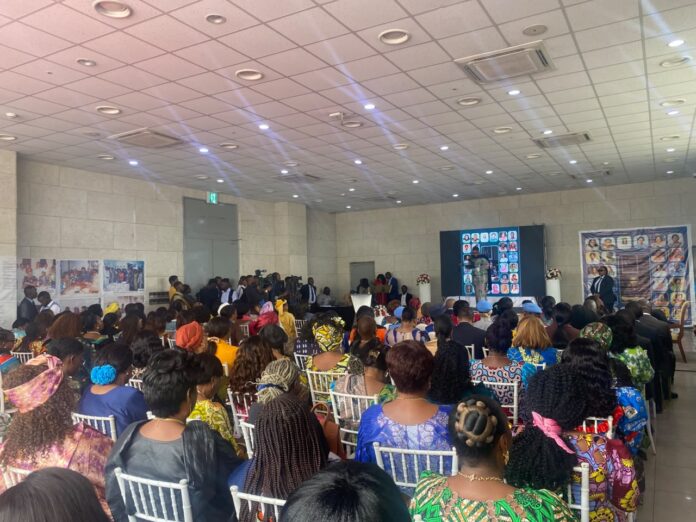 Première ministre remettant un certificat d'honneur à une femme pionnière lors de la cérémonie à Kinshasa