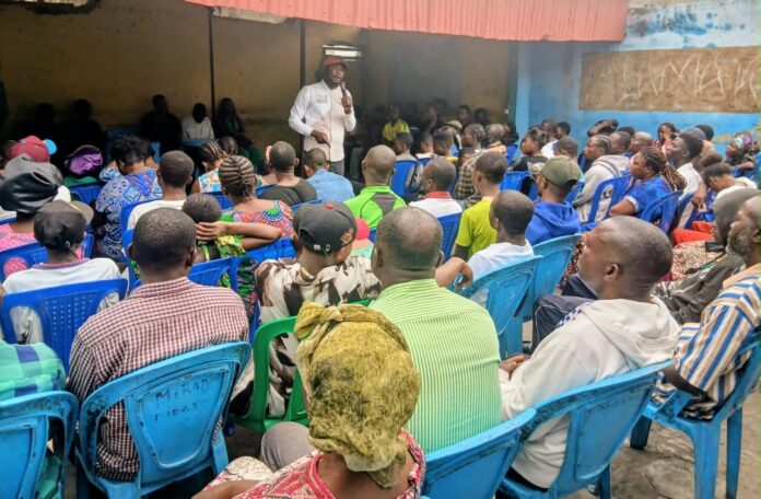 Foule rassemblée lors d'une rencontre citoyenne à Kinshasa, avec des participants levant les mains