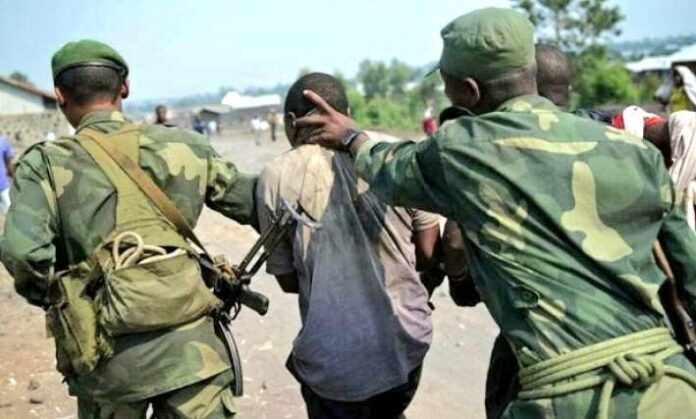 Soldat des FARDC menotté escorté par des militaires dans un secteur du Kwango