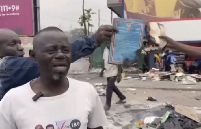 Restes de livres calcinés sur un trottoir de Kinshasa avec une épaisse fumée