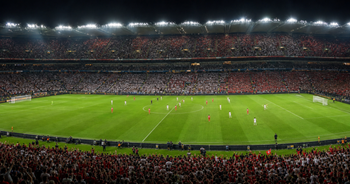 Vue large d un stade plein a Dublin avec une equipe rouge face a une equipe blanche.