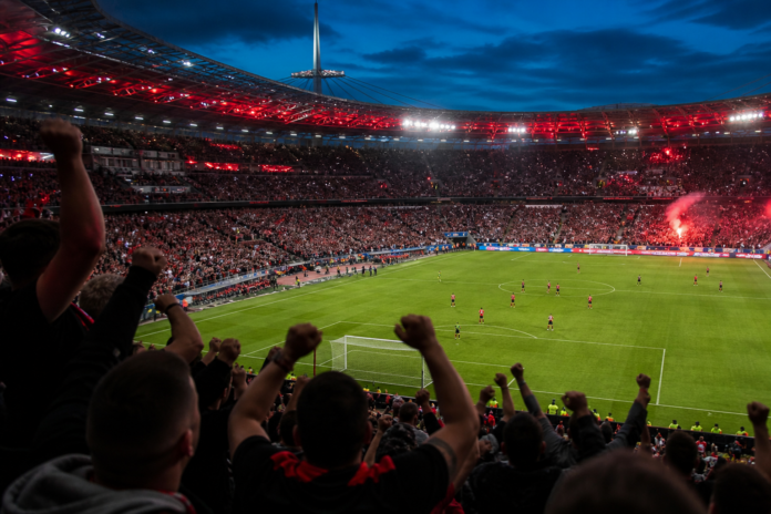 Illustration editoriale d un grand stade europeen en soiree apres la victoire de l AC Milan face a Manchester United.