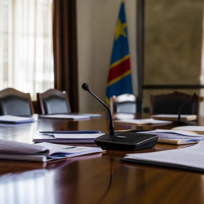 Réunion de responsables politiques congolais discutant autour d'une table dans une salle neutre