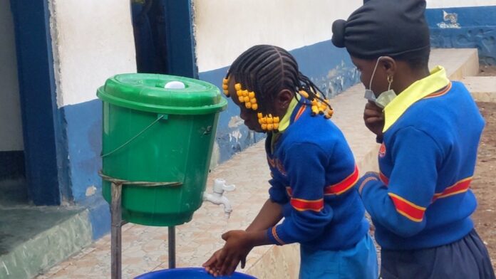 Dispositif de lavage des mains avec savon et affiches de prévention Ebola à l'entrée d'une école en RDC