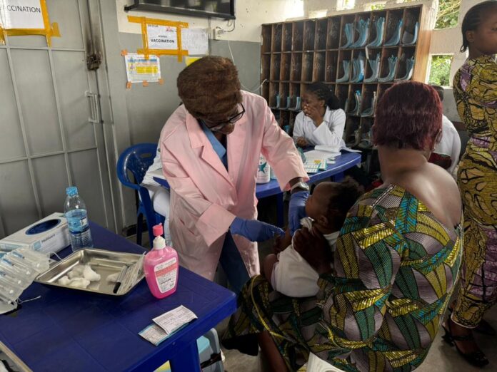 Campagne de vaccination contre la rougeole dans un centre de santé rural de l'est de la RDC, avec des infirmiers préparant des doses