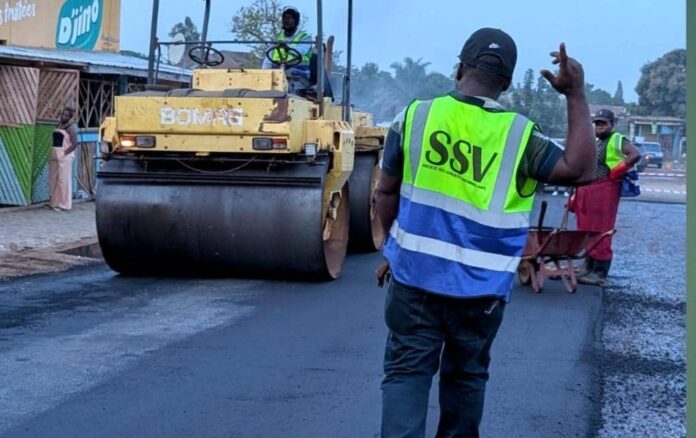 Chantier d'asphaltage avec poseuse d'enrobé et rouleau compresseur sur la rue Ziaka à Beni