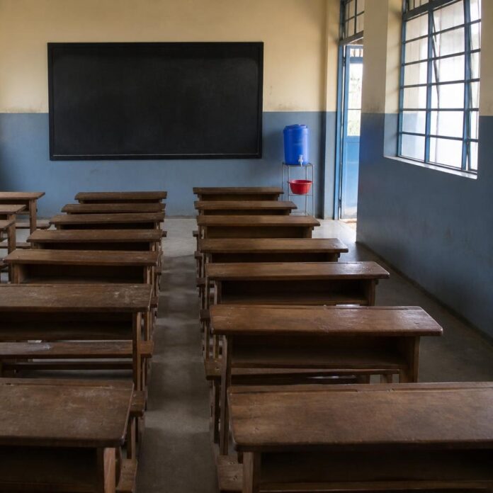 Salle de classe avec des pupitres en bois et un poste de lavage des mains à Beni, dans le contexte de la reprise des cours