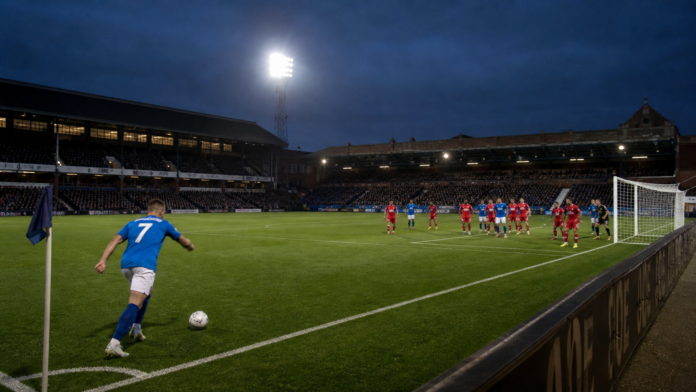 Joueurs anonymes disputant un corner dans un stade anglais éclairé