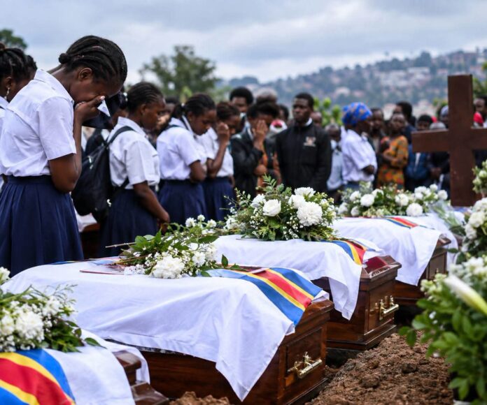 Cercueils recouverts de tissus et proches rassemblés au cimetière Ruzizi lors de l'inhumation des élèves morts dans l'incendie de Bukavu
