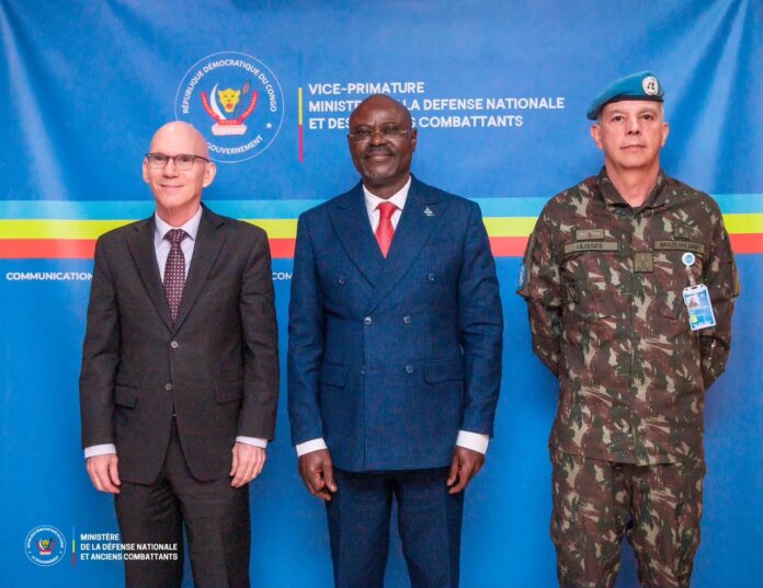 Salle de réunion officielle à Kinshasa avec documents, dossiers et microphones sur une grande table