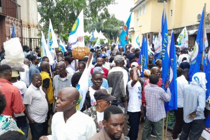 Dispositif policier et barrières dans une avenue de Kinshasa avant une marche politique, ambiance tendue