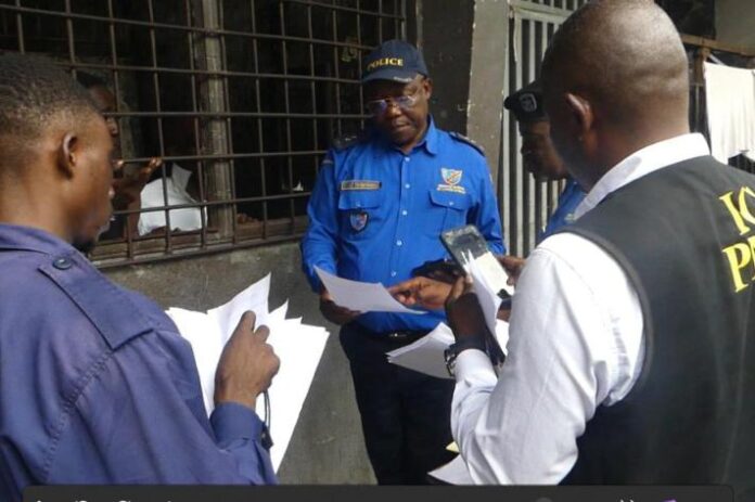 Véhicule de police banalisé et dossiers judiciaires devant un commissariat urbain à Kinshasa