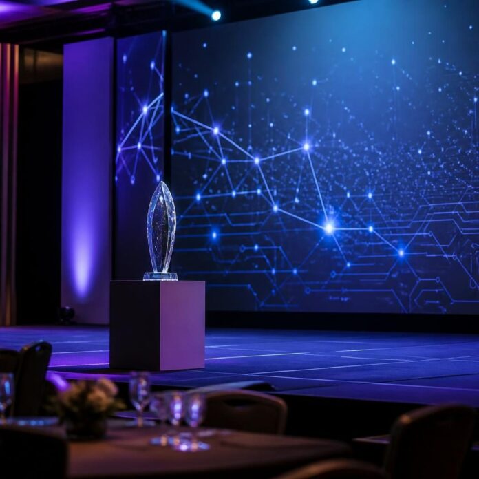 Cérémonie de remise de prix tech avec un grand écran, un trophée et un public applaudissant