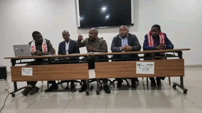 Conférence de presse avec micros et caméras dans une salle à Kinshasa, ambiance de dialogue politique