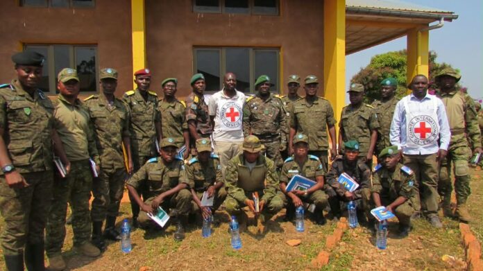 Militaires en treillis assis en rang dans une salle, un formateur du CICR presente les principes du droit humanitaire