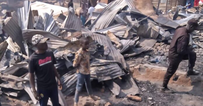 Habitations en planches calcinées après un incendie au quartier Kasika, à Goma, avec des débris et de la fumée