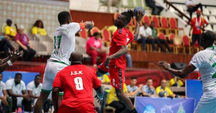 Ballon de handball posé sur un parquet de salle, fanions de clubs et ambiance de compétition africaine