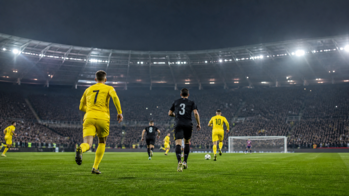 Joueurs anonymes disputant un match de football sous les projecteurs