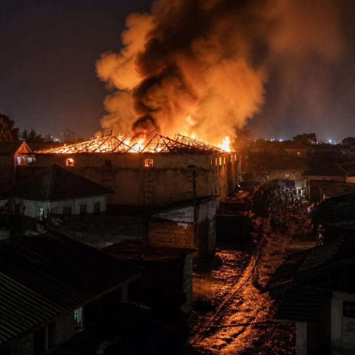 Flammes et fumée s'élevant de la salle des fêtes Bonne Auberge à Limete, Kinshasa, alors que des habitants tentent de maîtriser l'incendie