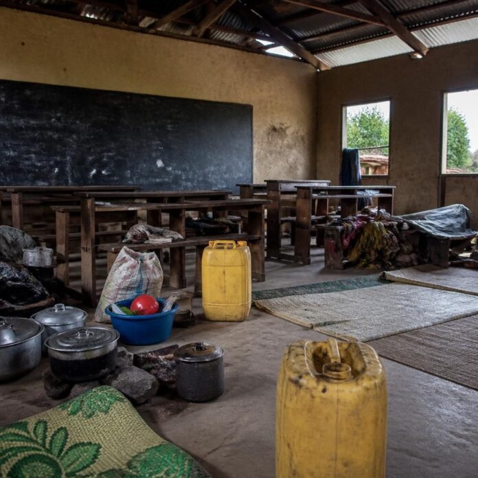 Salle de classe vide avec des bancs et un tableau noir, servant d'abri à des familles déplacées après les attaques à Mambasa