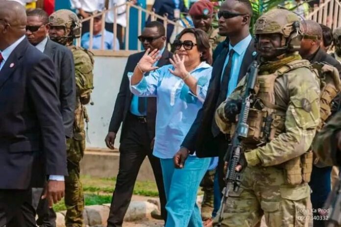 Vue de Tshikapa avec des véhicules officiels et une foule en attente près d’un bâtiment administratif