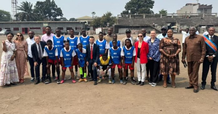 Terrain multisports communautaire à Kinshasa avec jeunes filles et habitants autour d’installations sportives