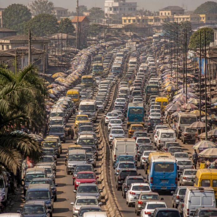 Files de véhicules et de minibus à l'arrêt sur une large avenue commerçante de Kinshasa aux heures de pointe