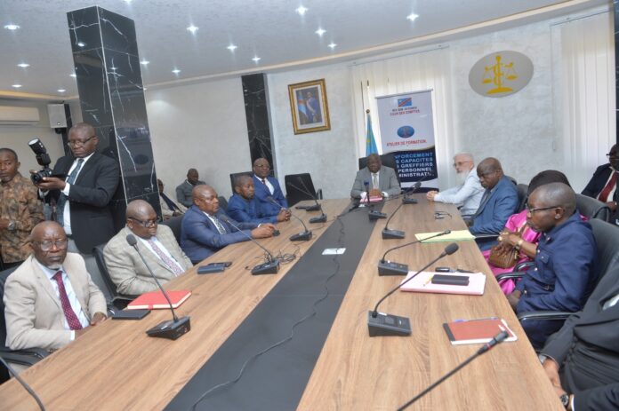 Session de formation professionnelle dans une salle de réunion à Kinshasa avec des participants concentrés sur des documents et ordinateurs