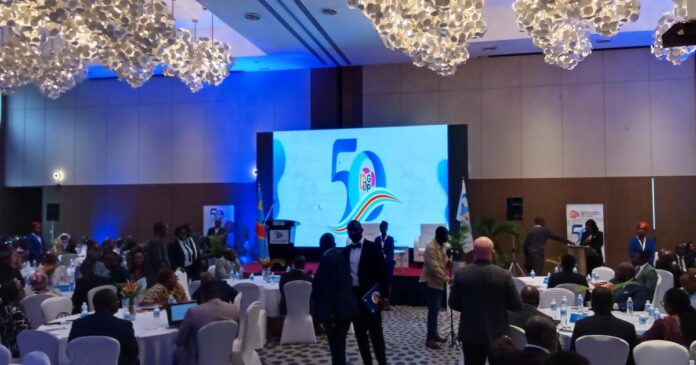 Salle de cérémonie officielle à Kinshasa avec invités réunis pour les 50 ans de la DGDP