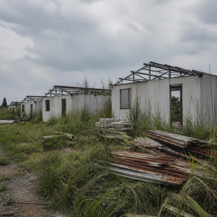 Maisons préfabriquées inachevées parmi les herbes sauvages sur le chantier de logements sociaux de Matadi-Kibala à Kinshasa