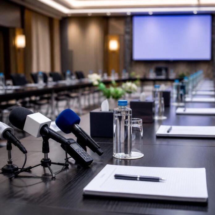 Salle de conférence avec micros et table ronde lors d'un débat sur le journalisme en RDC