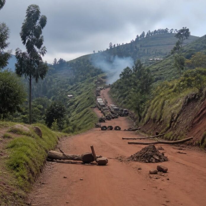 Route de terre coupée dans les collines du Nord-Kivu avec véhicules immobilisés et barricades de fortune