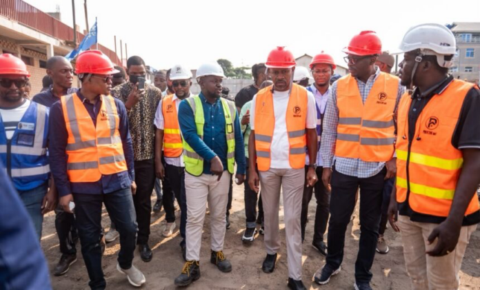Une délégation officielle en inspection sur un chantier urbain de la FUNA, à Kinshasa, sous un ciel tropical
