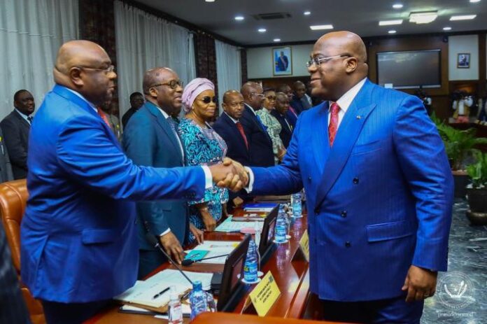 Table de conférence vide avec micros et drapeau national dans une salle à Kinshasa