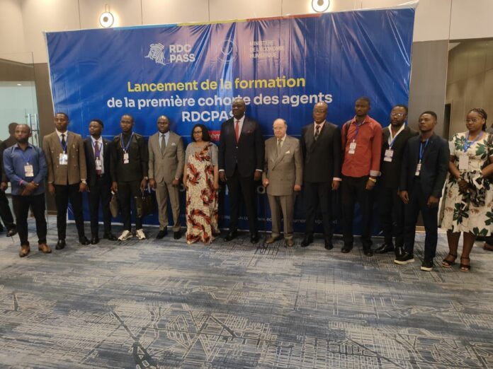 Salle de formation avec ordinateurs, dossiers et écrans de projection, illustrant l’enregistrement des agents du RDC-PASS à Kinshasa