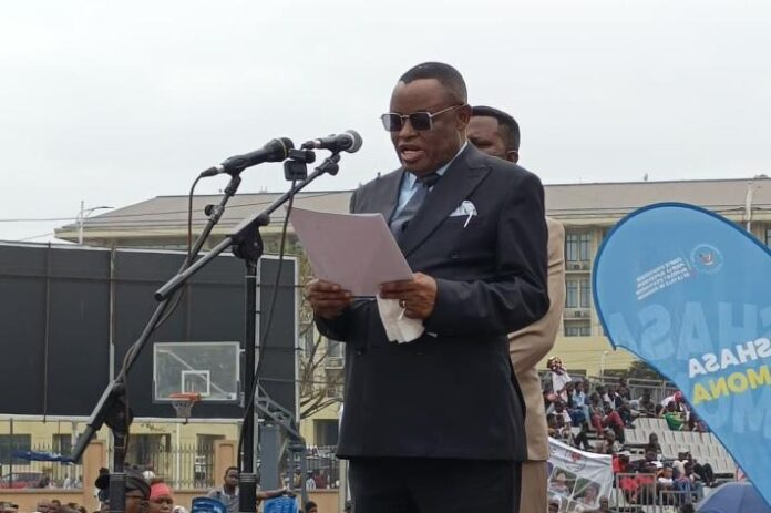 Foule nombreuse de membres de la société civile et personnalités dans une salle de cérémonie à Kinshasa écoutant un discours