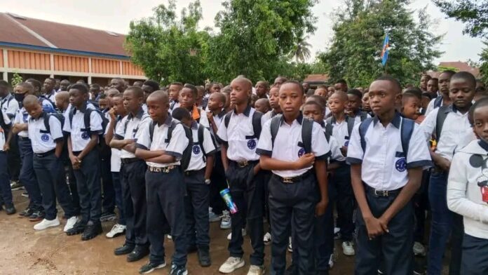 Des élèves se lavent les mains à l'entrée du Collège Maele à Kisangani, avec des seaux d'eau et du savon