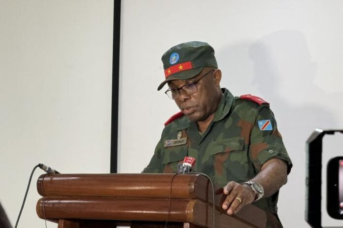 Podium de presse militaire avec microphones et documents, évoquant le retour du porte-parole des FARDC