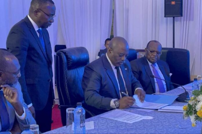 Documents officiels et drapeau de la RDC sur un bureau, évoquant la contestation de l’ordonnance sur le dialogue national
