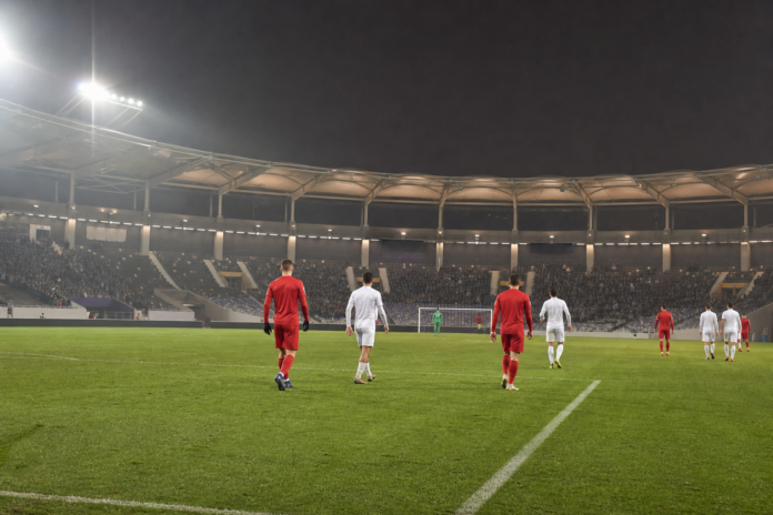 Joueurs anonymes sur une pelouse de football éclairée en nocturne