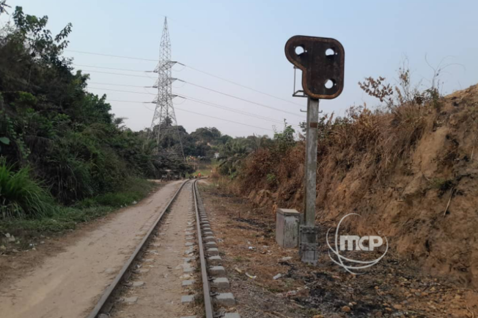 Rails rouillés, traverses dégradées et herbes folles sur la ligne ferroviaire Kinshasa-Matadi, avec des collines en arrière-plan