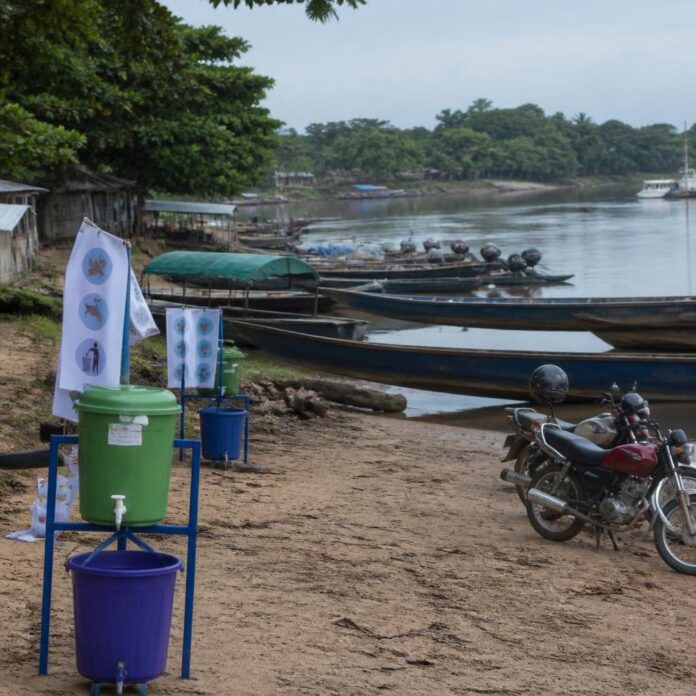 Bateaux et pirogues sur le fleuve Congo à Kisangani, avec agents de santé sensibilisant les voyageurs et conducteurs de motos