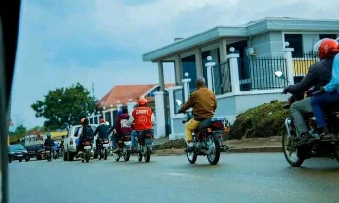 groupe de personnes en moto sur une route avec des batiments et des voitures en arriere-plan