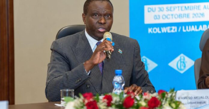 Salle de conférence institutionnelle avec pupitre, micros et documents, à Kolwezi