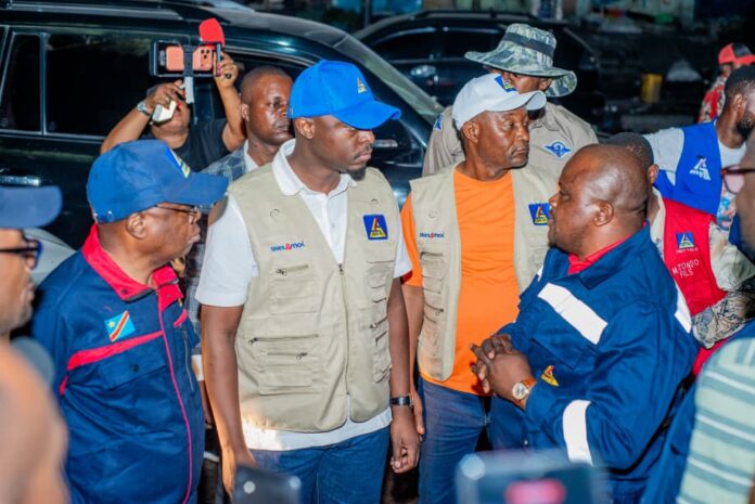 Pylônes et câbles électriques dans une rue de Kinshasa la nuit, éclairage public partiel