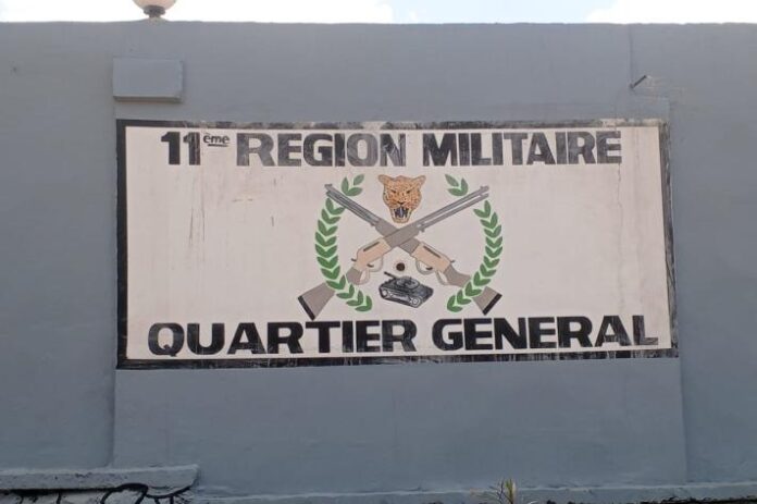 un panneau mural peint avec le texte '11ème REGION MILITAIRE QUARTIER GENERAL' et un blason avec une tête de léopard, deux fusils croisés,